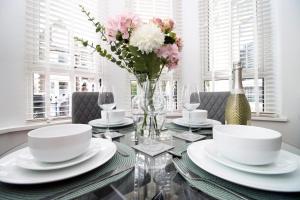 a dining room with a glass table with a vase of flowers at Luxury Apartment in Cardiff