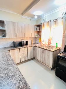a kitchen with wooden cabinets and a sink at Hibiscus Apartments in Ndola