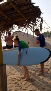 un grupo de personas de pie en la playa con una tabla de surf en Moragalla Beach Apartments, en Moragalla