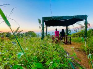 two people sitting on a picnic table under a canopy at Peacock Hill Glamp in Gampola