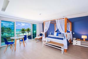 a bedroom with a bed and a table and chairs at Kembali Hotel Porto de Galinhas - Adults Only in Porto De Galinhas