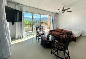 a living room with a bed and chairs and a television at Vistas a las Montañas y al Mar I Condominio Las Calandrias I Alberca I Wi-Fi in Ixtapa