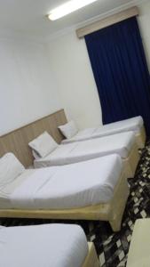 three beds in a room with a blue curtain at منازل المنال in Makkah
