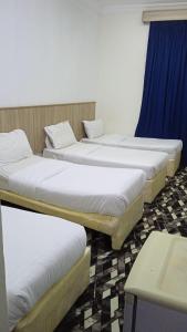 4 camas en una habitación con cortina azul en منازل المنال, en La Meca