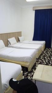 a row of four beds in a room with a table at منازل المنال in Makkah