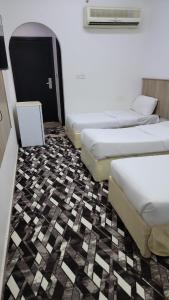 a room with three beds and a room with a floor with at منازل المنال in Makkah