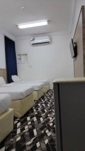 um quarto com uma fila de camas e uma televisão em منازل المنال em Meca