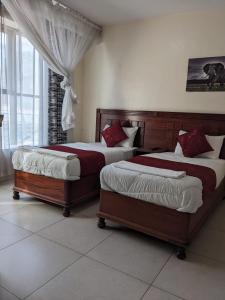 two beds sitting in a bedroom with a window at Epitome Times Hotel in Nairobi