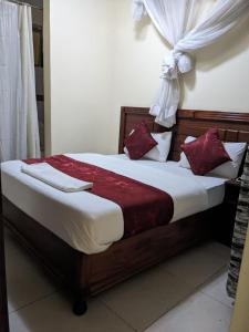 a bedroom with a wooden bed with red and white pillows at Epitome Times Hotel in Nairobi