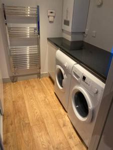 a washing machine in a kitchen with a wooden floor at Owlhoot Annexe in Sudbury