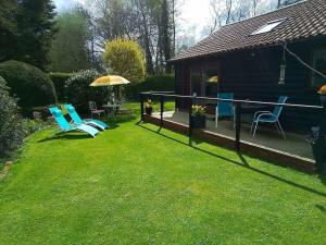 a yard with two chairs and an umbrella and a house at Owlhoot Annexe in Sudbury