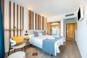 a hotel room with two beds and a chair at Hotel Vibra Beverly Playa in Paguera