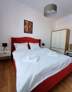 a bedroom with a large white bed with a red headboard at Bella Casa - ApartHotel in Dej