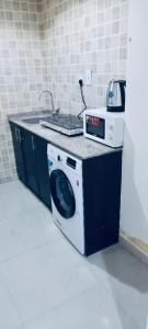 uma máquina de lavar roupa numa cozinha com um lavatório em Couples Room with Window smart TV Fridge em Dubai