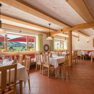 ein Restaurant mit weißen Tischen, Stühlen und Fenstern in der Unterkunft Sontheims Naturhotel & Spa in Maierhöfen