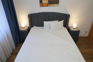 a large bed with two night stands with two lamps at Bovino Hotel in Raunheim