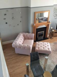 a living room with a chair and a clock on the wall at 2 bedroom apartment, great location for tourists in Liverpool