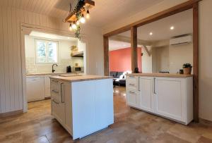 a large kitchen with white cabinets and a kitchen island at Le Quai in Saint-Vincent-de-Cosse