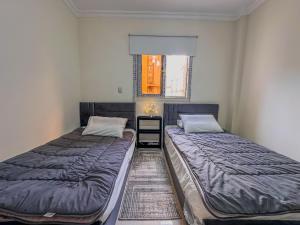2 camas individuais num quarto com uma janela em Joe Excellence Residence em Cairo