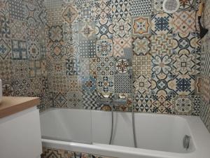 a bathroom with a tub with tiles on the wall at Top studio + Parking + Wifi in Toulon