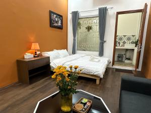 Cette chambre comprend un lit et une table fleurie. dans l'établissement Hanoi Old Quarter Inn, à Hanoï
