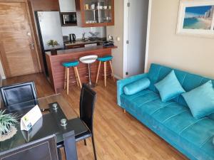 sala de estar con sofá azul y cocina en Delpino Propiedades Palmas del Mar, en Viña del Mar