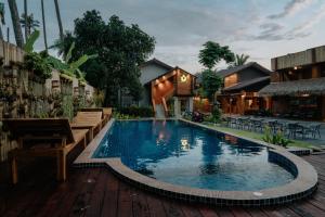 a swimming pool with a wooden deck and a building at U OLIVE Hotel in Ban Nua