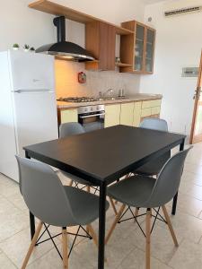 uma cozinha com uma mesa e cadeiras pretas e um frigorífico em Villa panoramica con giardino - Casa Valù em Cassano delle Murge