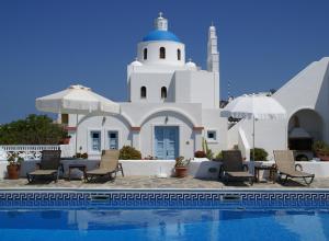 a pool in front of a building with a church at Aethrio Sunset Village - Oia in Oia