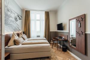 a bedroom with a bed and a desk and a window at Strandhotel Hohenzollern in Borkum