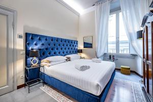 a bedroom with a large bed with a blue headboard at THREE APARTMENTS Via Roma in Florence