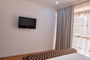 a room with a tv on the wall and a bed at Strata Homestay- Luxurious 2- Storey Townhouse in Baguio