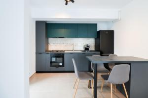a kitchen with blue cabinets and a table and chairs at Como Life Inn in Bragadiru