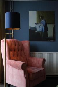 a living room with a pink chair and a lamp at Hotel West Inn in Hippolytushoef