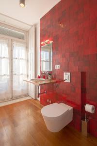 a red tiled bathroom with a toilet and a sink at Fil's Place in Porto