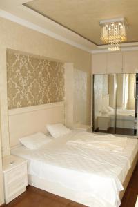 um quarto com uma cama branca e um lustre em Bueno Guest hause em Yerevan