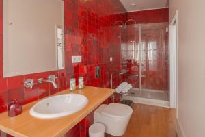 a red tiled bathroom with a sink and a toilet at Fil's Place in Porto