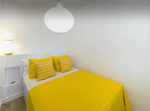 Habitación blanca con cama amarilla y almohadas amarillas. en Faro y Playa, en Morro del Jable