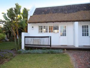 a white house with a bench in front of it at Seals Backpackers in Cape St Francis