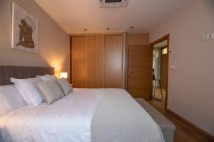 Schlafzimmer mit einem großen weißen Bett und Holzschränken in der Unterkunft EREA in Monforte de Lemos