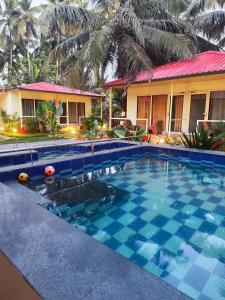 a swimming pool in front of a house at The Sunbliss Cottages in Morjim