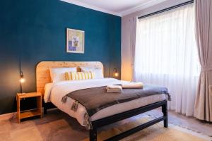 1 dormitorio con 1 cama grande y pared azul en Becca House Nakuru en Nakuru