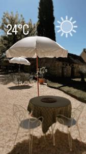 - une table avec un parasol et des chaises dans le sable dans l'établissement Maison Lou Piade, à Sarlat-la-Canéda
