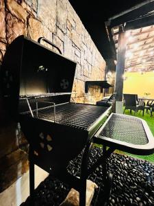 a black barbecue grill with a table and chairs at Relaxed Family Home by StayCo - Quiet Neighbourhood in Ayer Itam