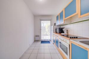 Il comprend une cuisine avec des placards bleus et du carrelage blanc. dans l'établissement Charmant Appartement avec Jardin, à Pessac