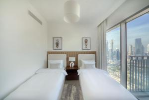 two beds in a room with a large window at Luxury Apartment in Dubai in Dubai
