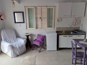 een keuken met paarse stoelen, een tafel en een wastafel bij Casa do Mato II in São Lourenço do Sul