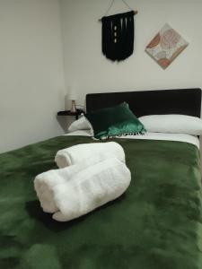 a white towel laying on a green bed at GURUS FR | Cerca al CC Arboleda, Circunvalar y Centro in Pereira