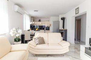 a white living room with a white couch and a kitchen at Bella Vita in Trilj