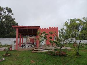 een rood huis met een tuinhuisje in een tuin bij Casa do Mato II in São Lourenço do Sul
